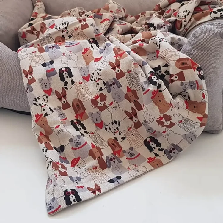 Pikowany dwustronny kocyk DOGS in the CITY z wypełnieniem z polaru, ręcznie wykonany w Niemczech, zewnętrzna warstwa 100% bawełna OEKO-TEX®, odporny na sierść i mechacenie, idealny jako narzutka na legowisko lub przenośne miejsce odpoczynku dla psa.